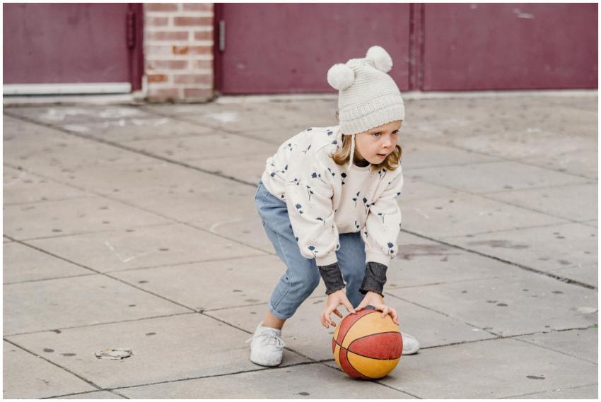 A young child plays with a basketball on a concret