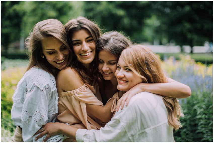 Four smiling women joyfully embrace in a lush gree