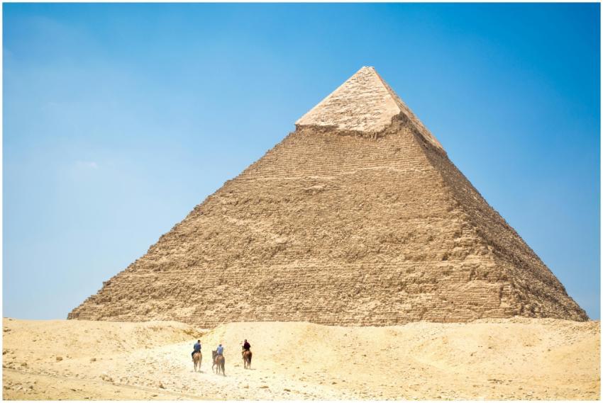 Iconic Giza Pyramid with riders on camels under br