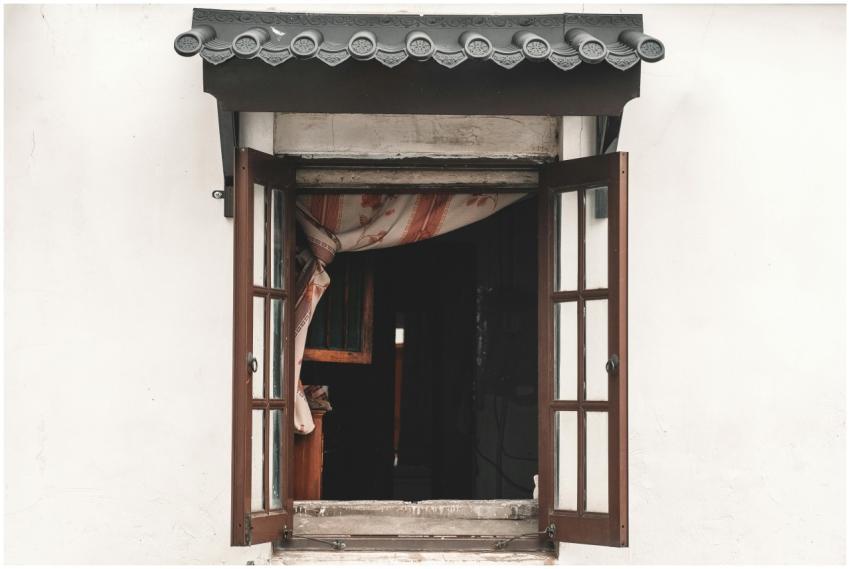 View of an open window with a wooden frame and cur