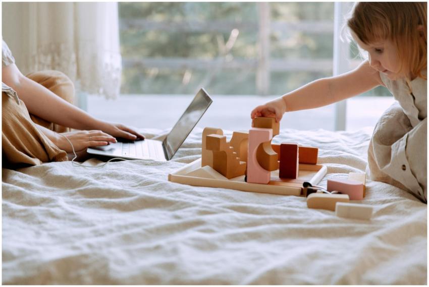 A child playing with blocks on a bed beside a pare