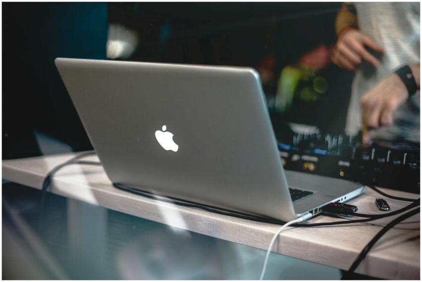 A DJ uses a laptop and audio mixer for a live musi