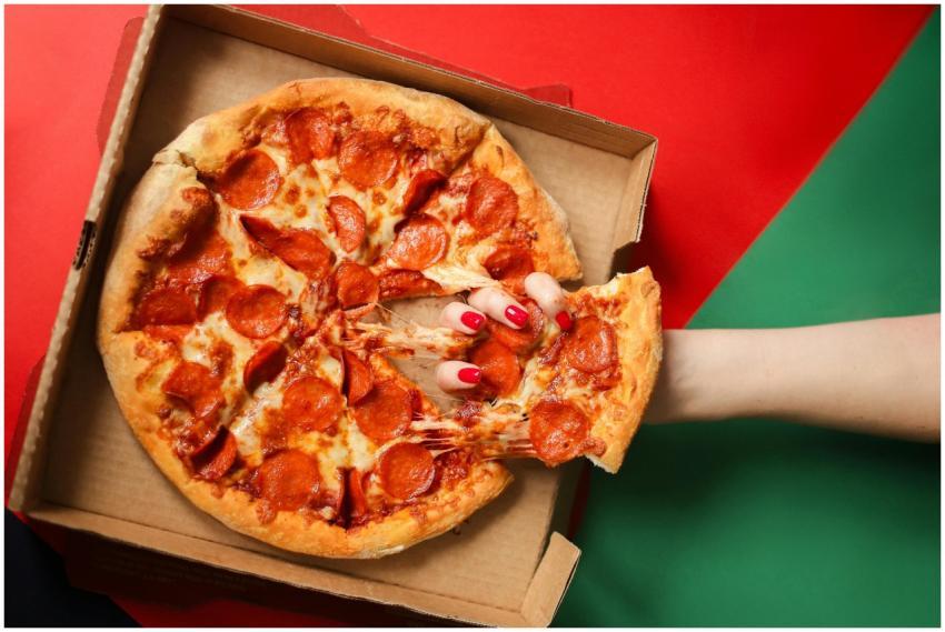 Fresh pepperoni pizza being pulled from the box. P