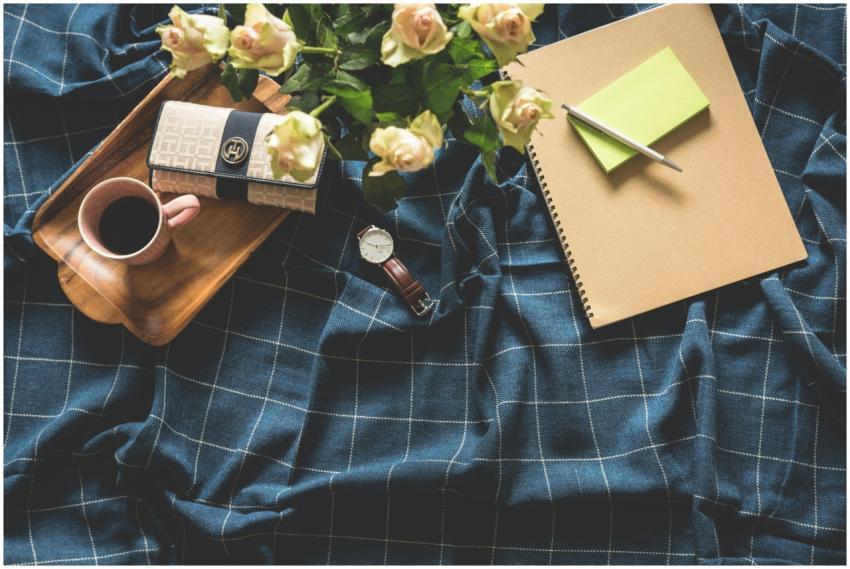 A cozy flatlay showing coffee, roses, notebook, an