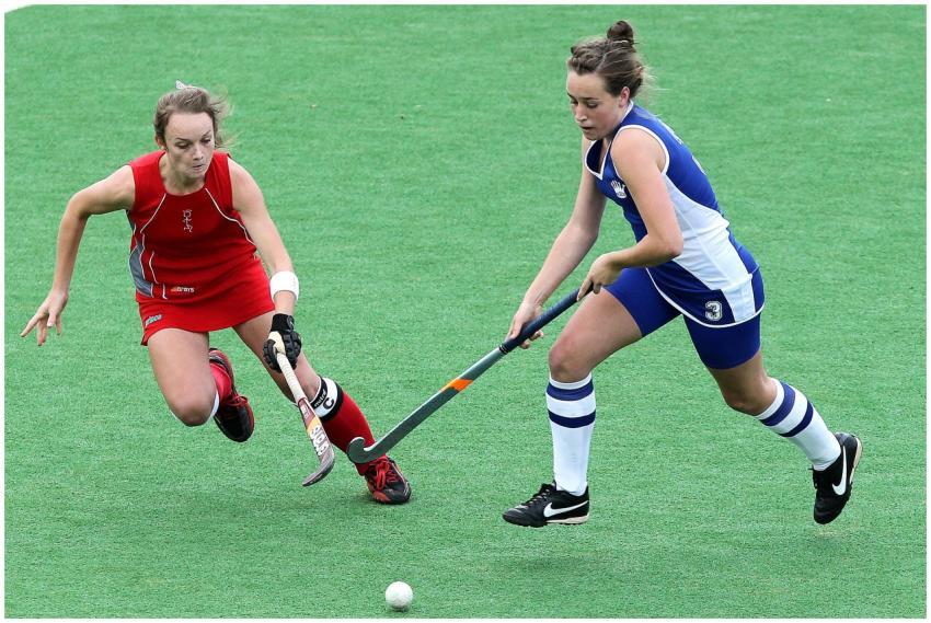 Two female athletes compete in a dynamic field hoc