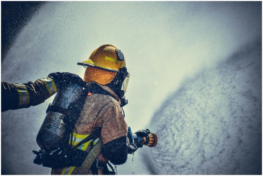 A brave firefighter in protective gear sprays wate