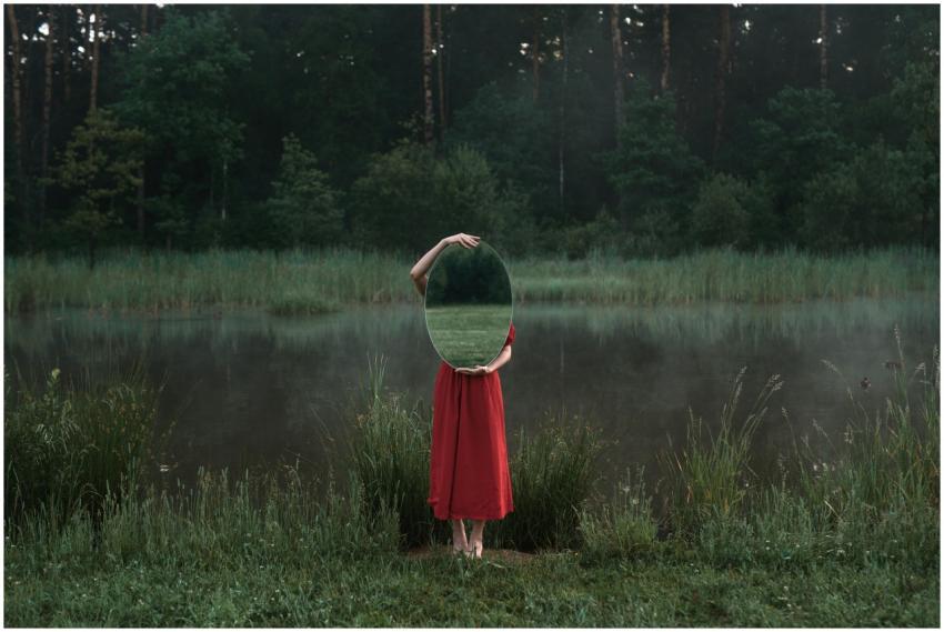 Artistic photo of a woman in nature holding a mirr