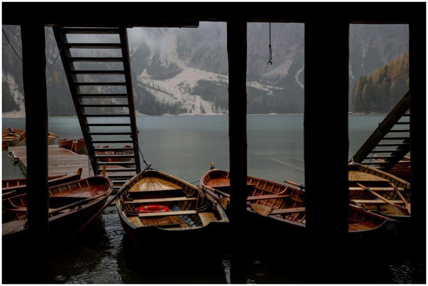 Wooden boats moored under a pier, reflecting tranq