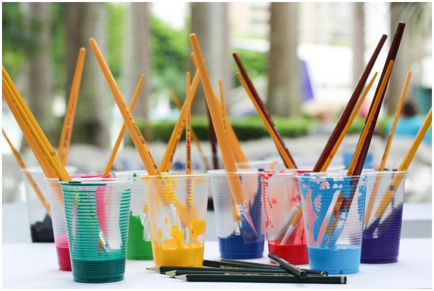 Vibrant paint brushes and pencils in plastic cups