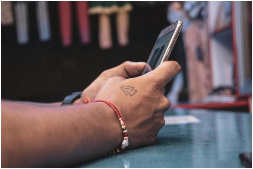 Detailed view of a hand with a tattoo holding a sm
