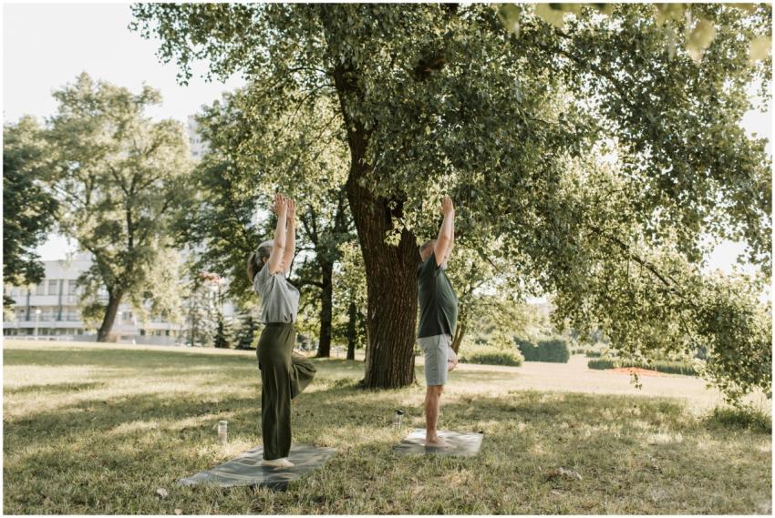 A man and woman practicing yoga outdoors in a sunn