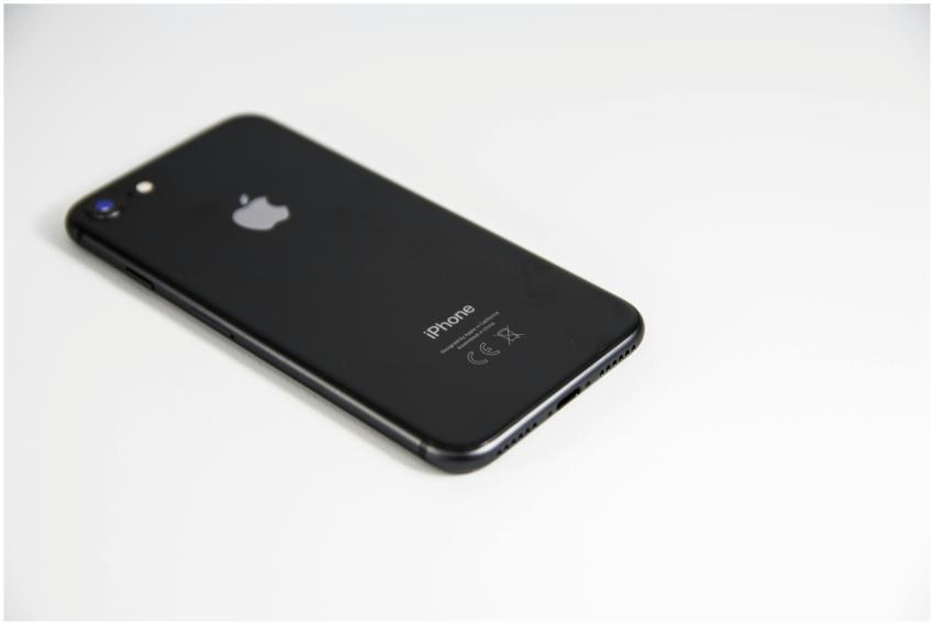 Black smartphone placed on a clean white surface,