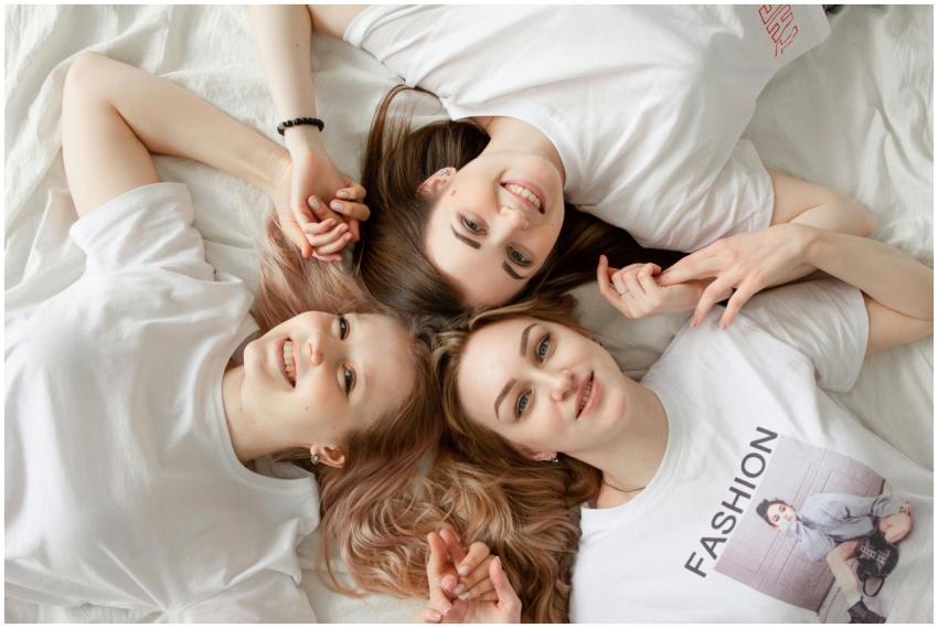 Three young women lying on a bed, smiling and enjo
