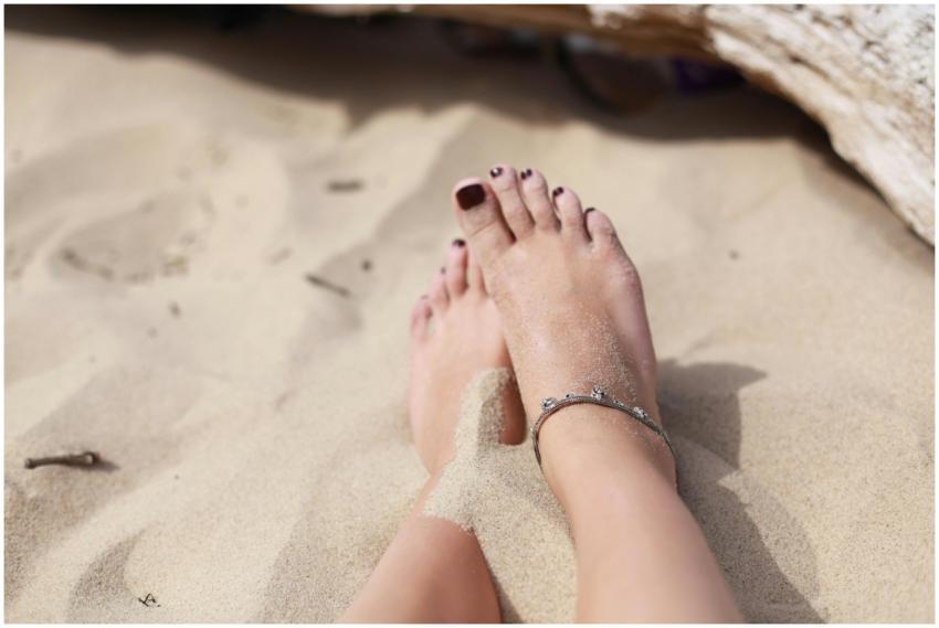 Close-up of feet in sand wearing an anklet, captur