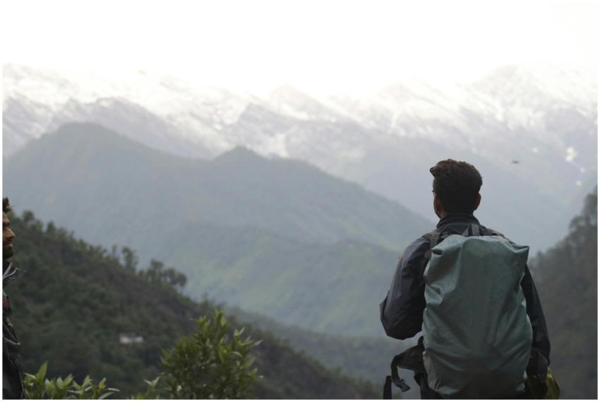A hiker enjoys a peaceful view of the snow-capped