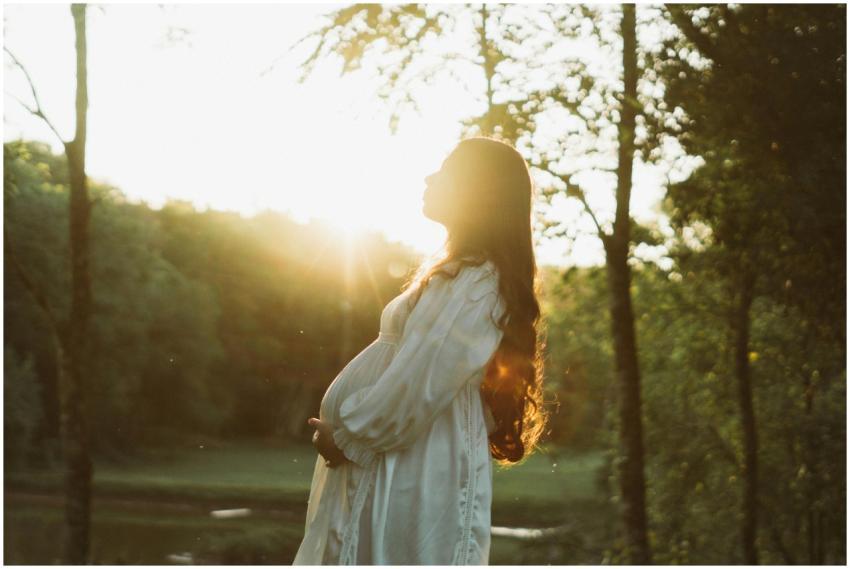 Pregnant woman in white dress enjoying a sunset in