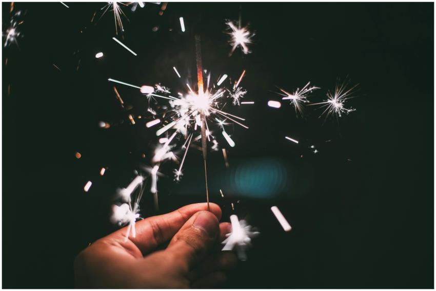 A hand holding a sparkler glowing brilliantly in t