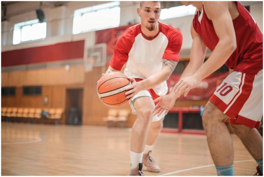 Two male basketball players practicing dribbling i