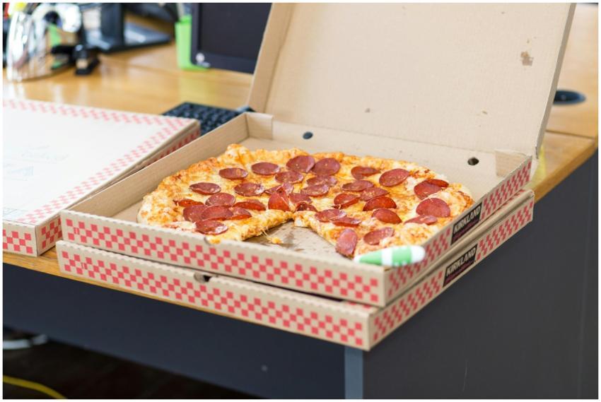 Delicious pepperoni pizza in an open box on a desk