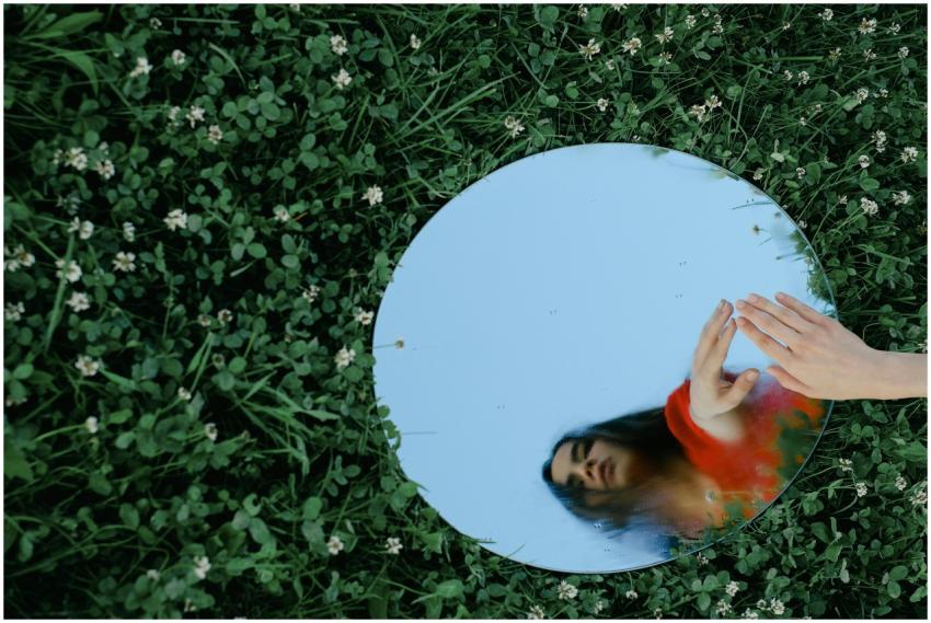 Artistic shot of a woman reflected in a mirror pla