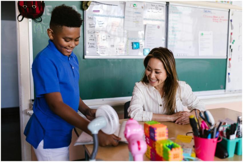 A smiling teacher assisting a student in an inspir