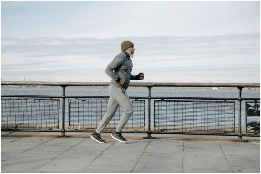 Elderly man running along waterfront, embracing a