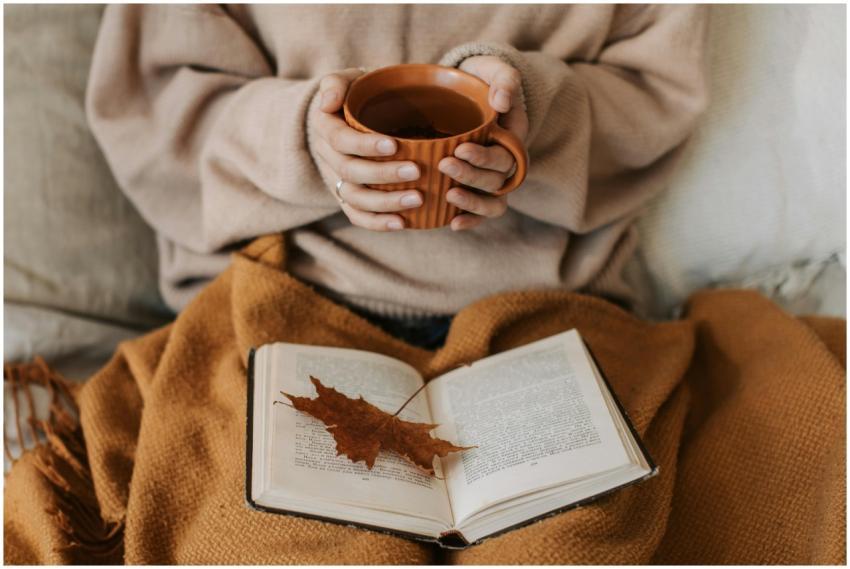 A woman enjoys a cozy autumn day, holding a tea mu