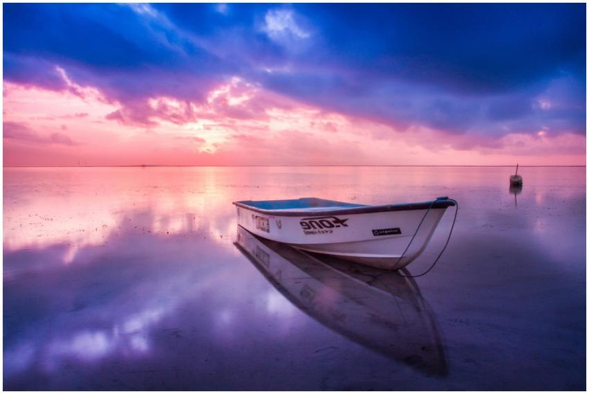 A tranquil scene of a boat at sunrise, reflecting