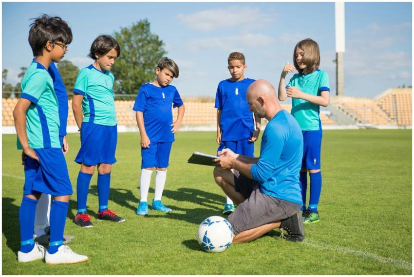 Coach guiding young soccer players on a lush green