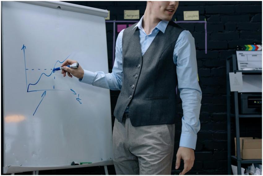 A businessman drawing a graph on a whiteboard duri