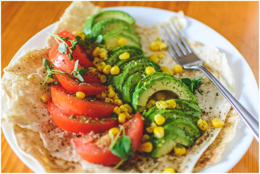 A vibrant salad with avocado, tomato, and corn on