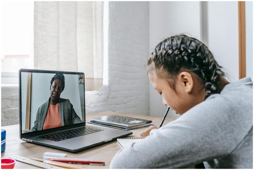 Side view of focused Asian schoolgirl sitting at w