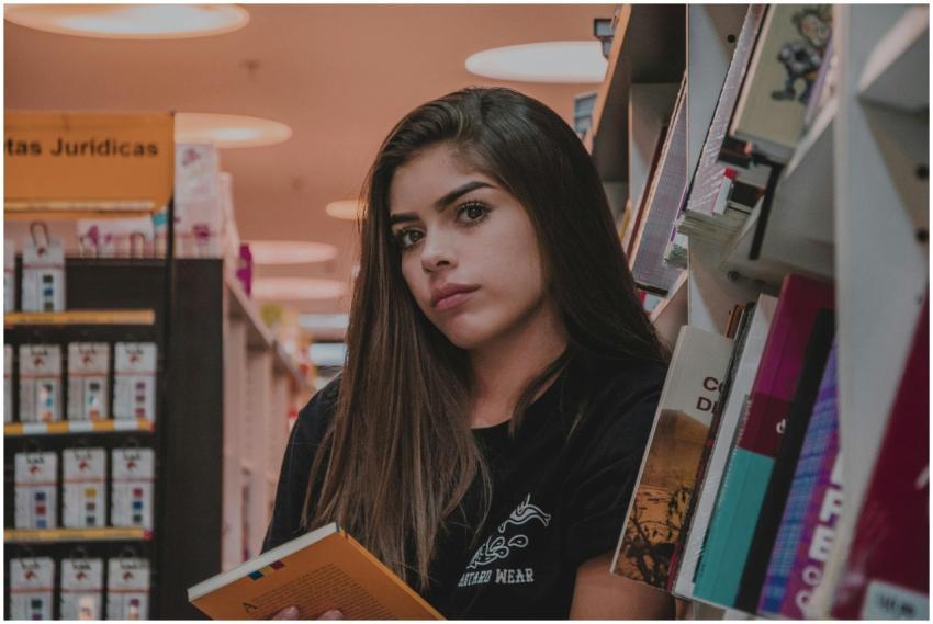 A young woman with long hair reading a book in a c