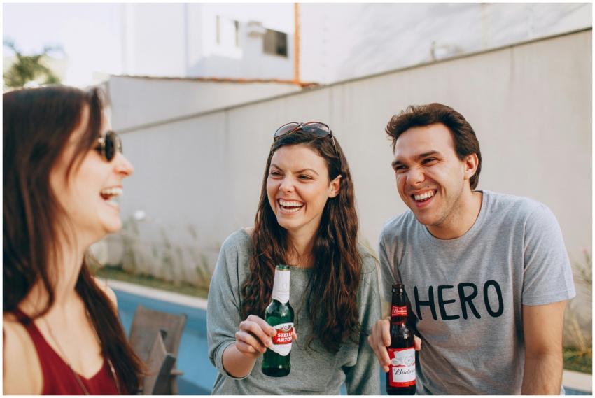 Three friends laughing and enjoying drinks outdoor