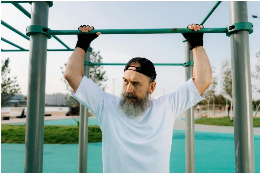 Senior man with beard performing pull-ups on monke