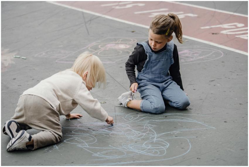 Two young children creatively drawing with chalk o