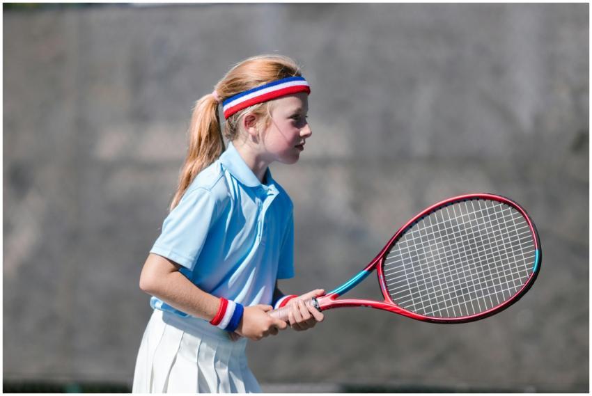 A young girl engaged in tennis practice on an outd