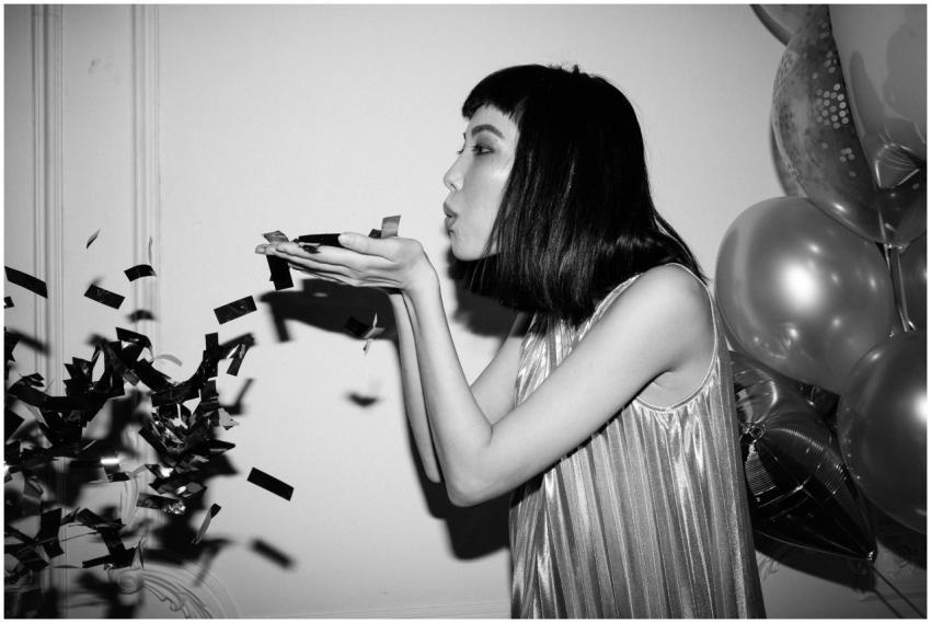 A stylish Asian woman in a party setting blows con