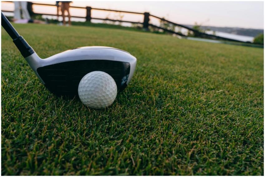 A close-up image of a golf ball and club on lush g