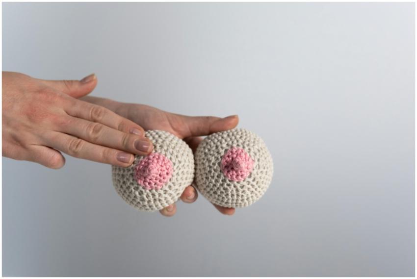 Hand touching knitted yarn breasts for breast canc