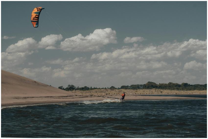 A kitesurfer expertly glides over the waves along