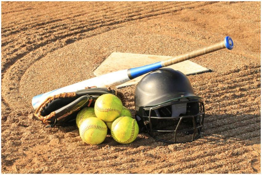 Close-up of baseball and softball gear on a dirt f