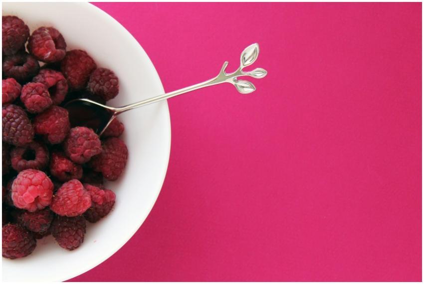 A bowl of fresh raspberries with a spoon on a vibr