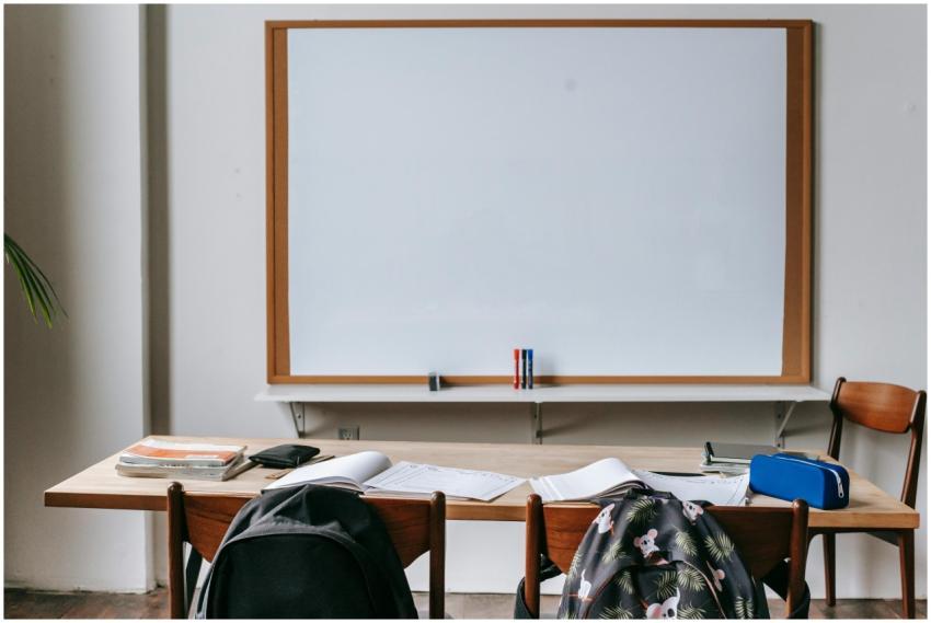 Empty classroom with wooden desks, chairs, and a l