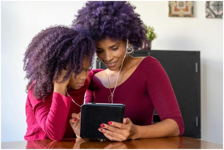 A mother and daughter sharing headphones while usi