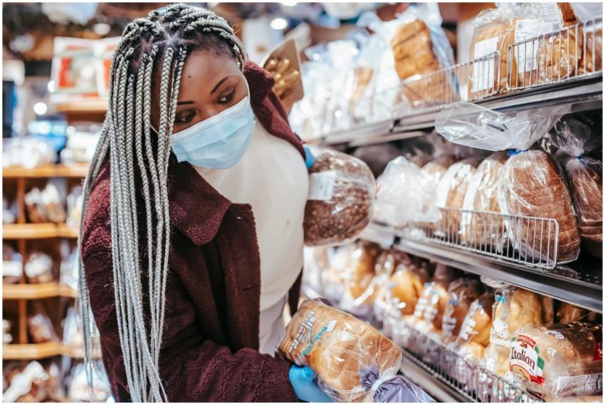 African woman selects bread in a grocery store dur