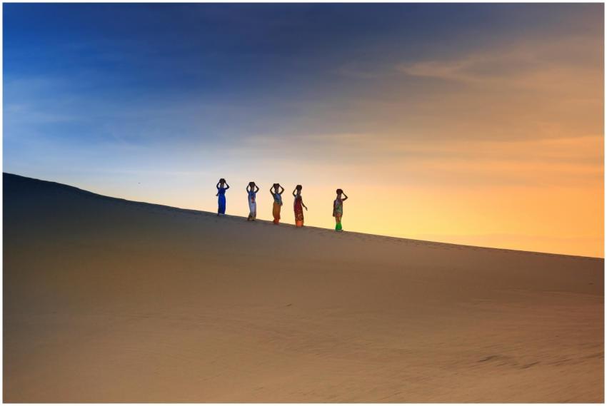 Women in colorful attire silhouetted against a dra