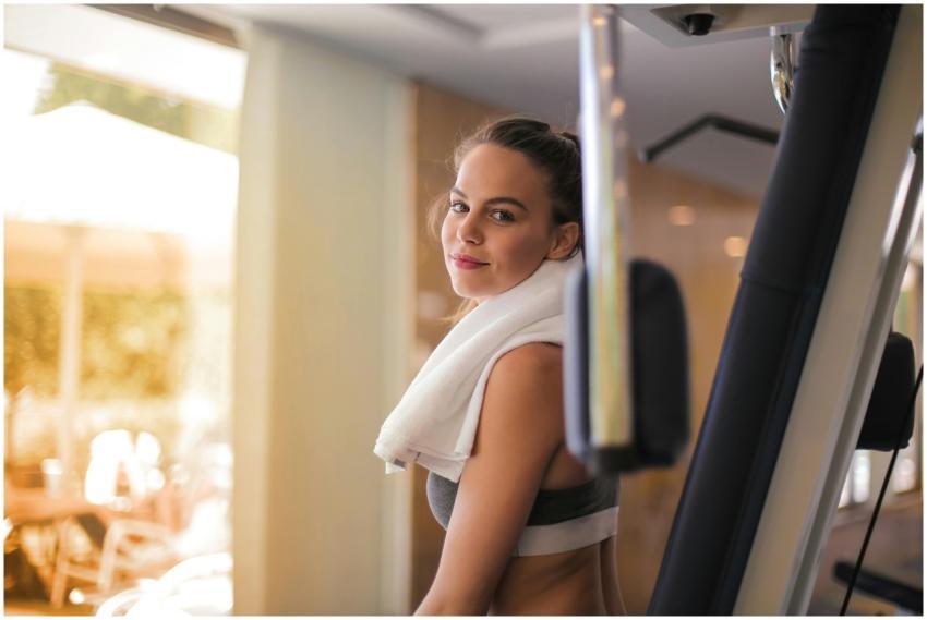 Young woman exercising in a gym with a towel aroun