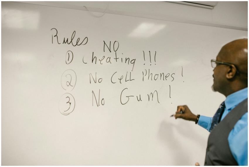 A teacher writes important classroom rules on a wh
