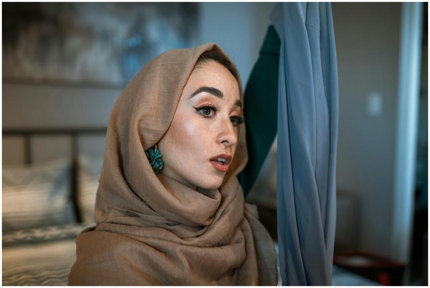 Portrait of a woman applying hijab indoors, showca